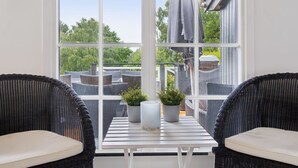 Una habitación con un ventanal grande, muebles de mimbre y plantas en macetas.