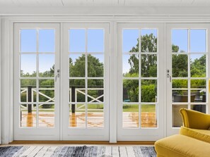 Ein Zimmer mit einer großen Schiebeglastür, die auf eine Terrasse im Freien führt.