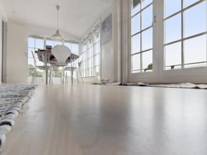Una habitación amplia con un gran ventanal, una mesa de comedor con sillas y una lámpara colgante.