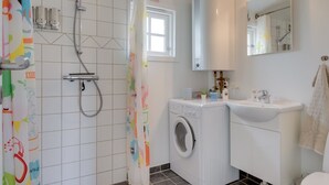 Ein Badezimmer mit Dusche, Waschmaschine, Spüle und Toilette.