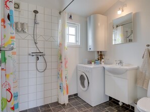 Ein Badezimmer mit Dusche, Waschmaschine, Spüle und Toilette.