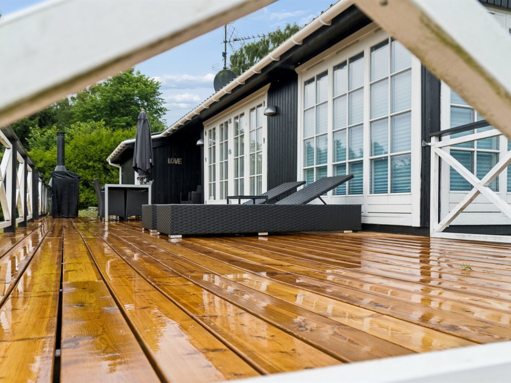 A wooden deck with a black outdoor seating area and a building with large windows in the background.