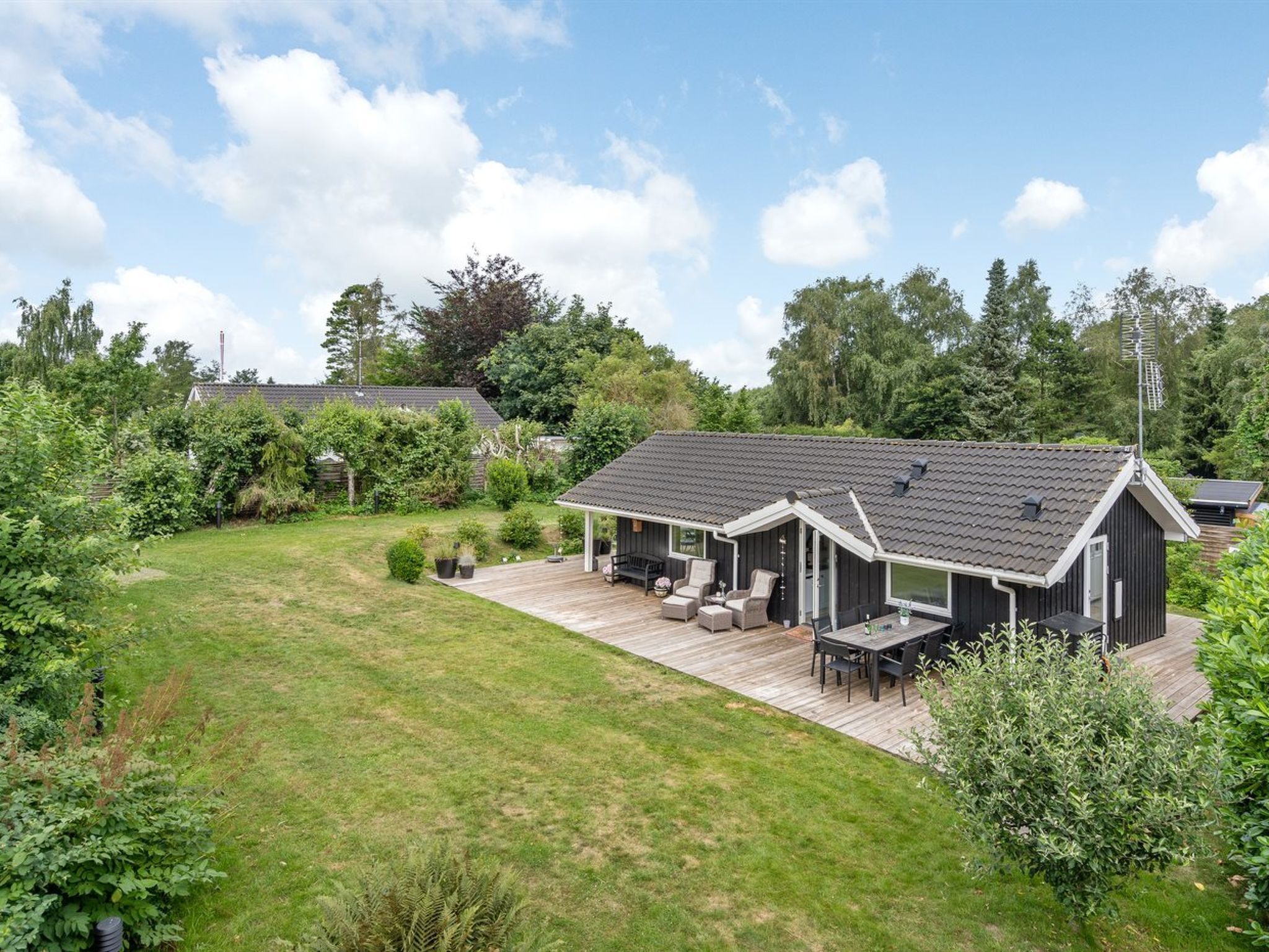 Een modern huis met een ruim terras, een overdekte zithoek en een verzorgd gazon.