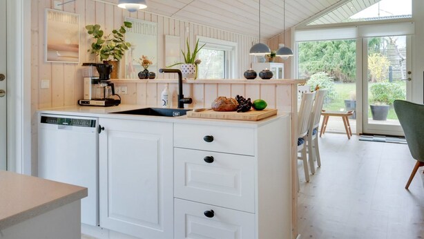 A modern kitchen with wooden paneling, a central island with a sink, and pendant lighting.