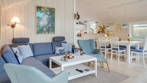 A spacious living area with a blue sofa, a white coffee table, and a dining table with chairs.