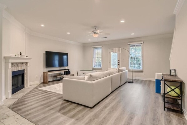 Relax in this stylish living room with a large flat-screen TV, comfortable sofa, and cozy fireplace.
