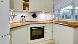 Una cocina compacta con muebles blancos, horno integrado y ventana que proporciona luz natural.