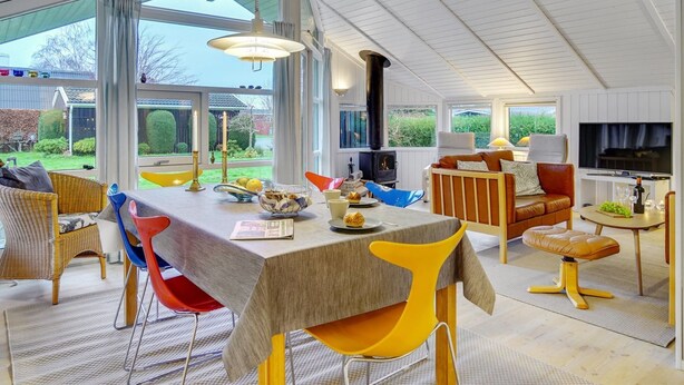 Un comedor amplio con una mesa larga, sillas coloridas y una chimenea moderna.