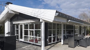 Un patio couvert, doté d’une structure vitrée, de mobilier d’extérieur et offrant une vue sur le paysage environnant.