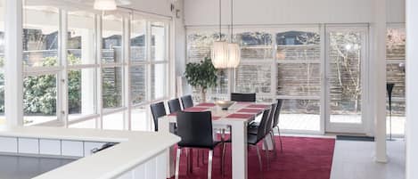 A dining area with a table set for six, surrounded by chairs, a red carpet, and a hanging light fixture.