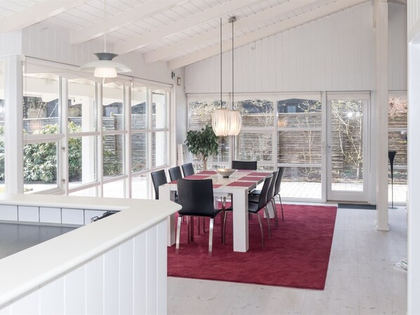 A dining area with a table set for six, surrounded by chairs, a red carpet, and a hanging light fixture.