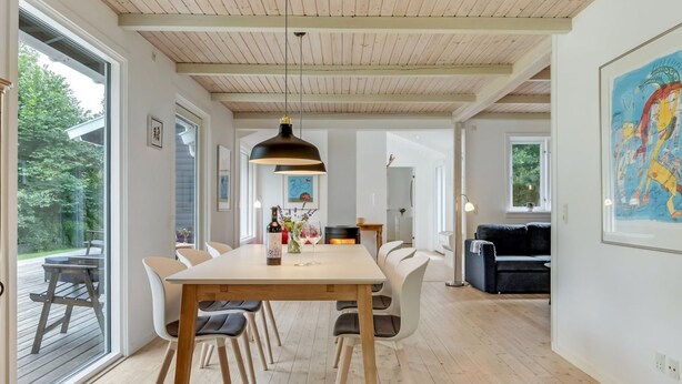 A spacious dining area with a wooden table and chairs, a pendant light, and a view of the outdoors.