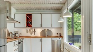 A modern kitchen with white cabinetry, stainless steel appliances, and a wooden countertop.