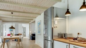 A modern kitchen with stainless steel appliances, a wooden dining table, and pendant lighting.