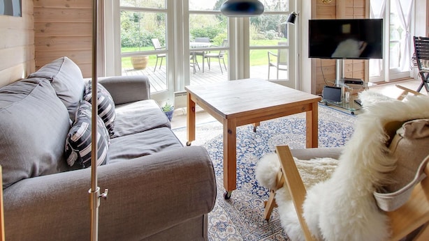 Una sala acogedora con un sofá, una mesa de centro de madera, un televisor y un perro.
