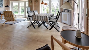 Interior de madera con una mesa de comedor, sillas, un sofá y una zona de cocina.