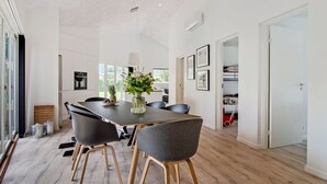 A modern dining area with a wooden table, black chairs, and a vase of flowers.
