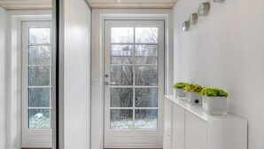 A hallway with a white door, a white console table with potted plants, and a wall-mounted clock. - "Amine" - 700m from the sea by Interhome (Hornbæk)