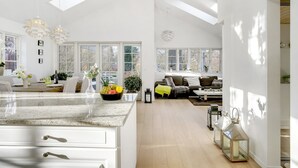 A spacious kitchen with a large island, a dining area with a table set for four, and a living room with a sofa and a coffee table. - "Amine" - 700m from the sea by Interhome (Hornbæk)