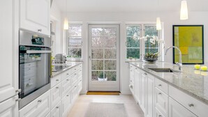 A modern kitchen with white cabinetry, a built-in oven, and a large window with a view of trees. - "Amine" - 700m from the sea by Interhome (Hornbæk)