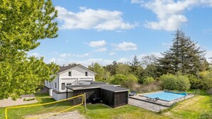 Una propietat residencial amb piscina, pati tancat i casa amb teulada inclinada.