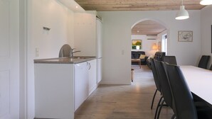 Una cuina moderna amb armaris blancs, taulell de granat i rentaplats integrat.