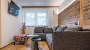 Ein modernes Wohnzimmer mit einem grauen Sofa, einem kleinen runden Tisch und einem floralen Pouf.