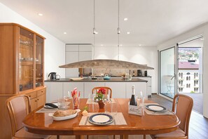 A modern kitchen with a large island, wooden cabinetry, and a dining area with a wooden table set for two. - Appartamento Lago e Monti - Garage & Terrace in Locarno (Locarno)