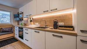 Une cuisine moderne avec des meubles blancs, un plan de travail en bois et une cuisinière intégrée.