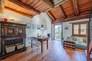 Una habitación amplia con techo de madera, una mesa de comedor con sillas, un sofá y una chimenea.