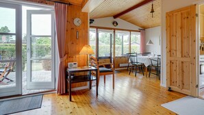 A cozy room with wooden floors, a dining area with chairs and a table, a radio, and a clock on the wall. - "Siem" - 650m from the sea by Interhome (Væggerløse)