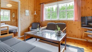 A cozy cabin-style room with a wooden interior, a dining area with a table and chairs, a bed, and a television. - "Siem" - 650m from the sea by Interhome (Væggerløse)