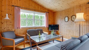 A cozy cabin interior with wooden walls, a sofa, chairs, a dining table, and a TV. - "Siem" - 650m from the sea by Interhome (Væggerløse)