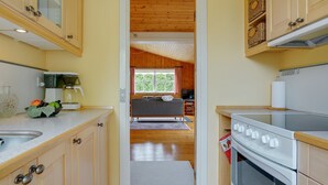 A compact kitchen with wooden cabinets, a stove, and a window overlooking a living area. - "Siem" - 650m from the sea by Interhome (Væggerløse)