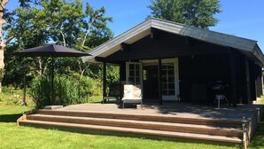 A modern house with a covered patio, a grill, and a large umbrella. - "Freyja" - 800m from the sea by Interhome (Væggerløse)