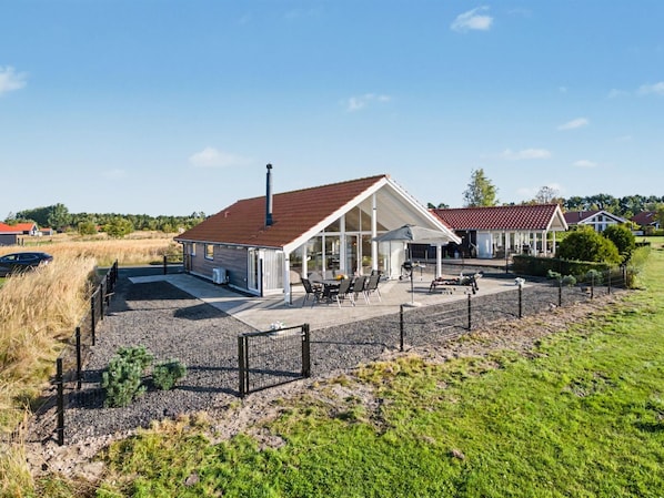 A house with a covered patio, a chimney, and a fenced yard.