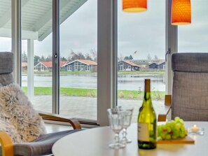 Enjoy a serene view of the water from this stylish room, featuring a round table with wine and a fruit arrangement.