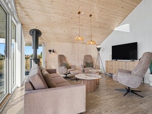 Un salon moderne avec un grand canapé, deux fauteuils, une table basse et un téléviseur.