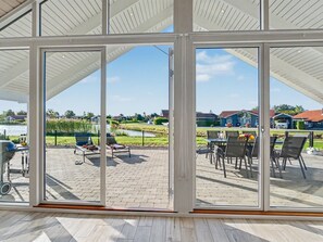 Ein überdachter Patio-Bereich mit Blick auf eine Wohngegend, Gartenmöbel und einem Grill.