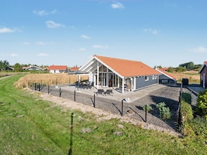 A modern house with a covered patio, a fenced yard, and a view of the surrounding area.