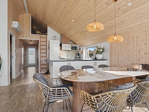 A spacious kitchen with a central island, wooden ceiling, and modern appliances.