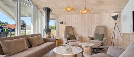 A modern living room with a large window, a fireplace, two armchairs, a sofa, and a coffee table.