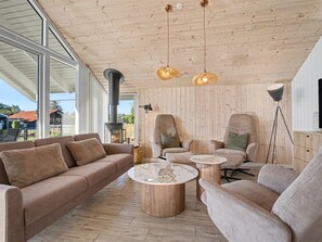 Ein modernes Wohnzimmer mit einem großen Fenster, einem Kamin, zwei Sesseln, einem Sofa und einem Couchtisch.