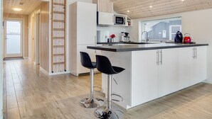 Une cuisine moderne dotée d’un îlot central, de meubles blancs et d’un plafond en bois.