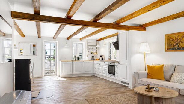 Una cocina moderna con armarios blancos, techo de madera y suelo con diseño de espiga.