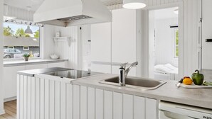 Una cucina moderna con mobili bianchi, un lavello in acciaio inossidabile e un'ampia finestra con vista sull'esterno.