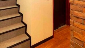 A staircase with a wall-mounted elevator, a wooden ceiling, and a brick wall. - Guest House Siesta (Tokyo)