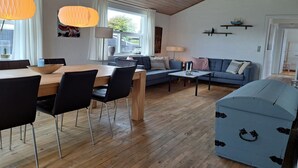 A modern living room with a wooden dining table, blue sofa, and a blue chest of drawers. - "Falk" - 900m from the sea by Interhome (Skagen)