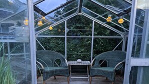 A greenhouse with two wicker chairs and a small table, surrounded by glass panels and wooden flooring. - "Falk" - 900m from the sea by Interhome (Skagen)