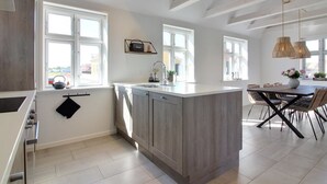 A modern kitchen with a large island, built-in appliances, and ample natural light from large windows.